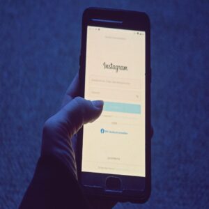 Telefon s aplikací Instagram a symbol práva znázorňující legálnost nákupu sledujících