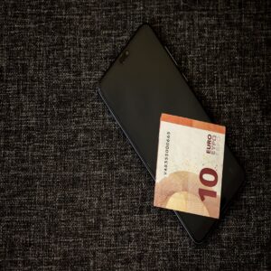Telefon s aplikací TikTok a eurové mince symbolizující cenu sledujících a lajků