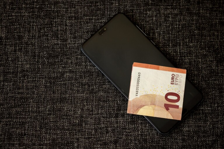 Telefon s aplikací TikTok a eurové mince symbolizující cenu sledujících a lajků